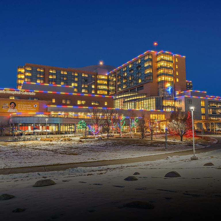 Large community building with multicolor lighting along its upper floors at night.