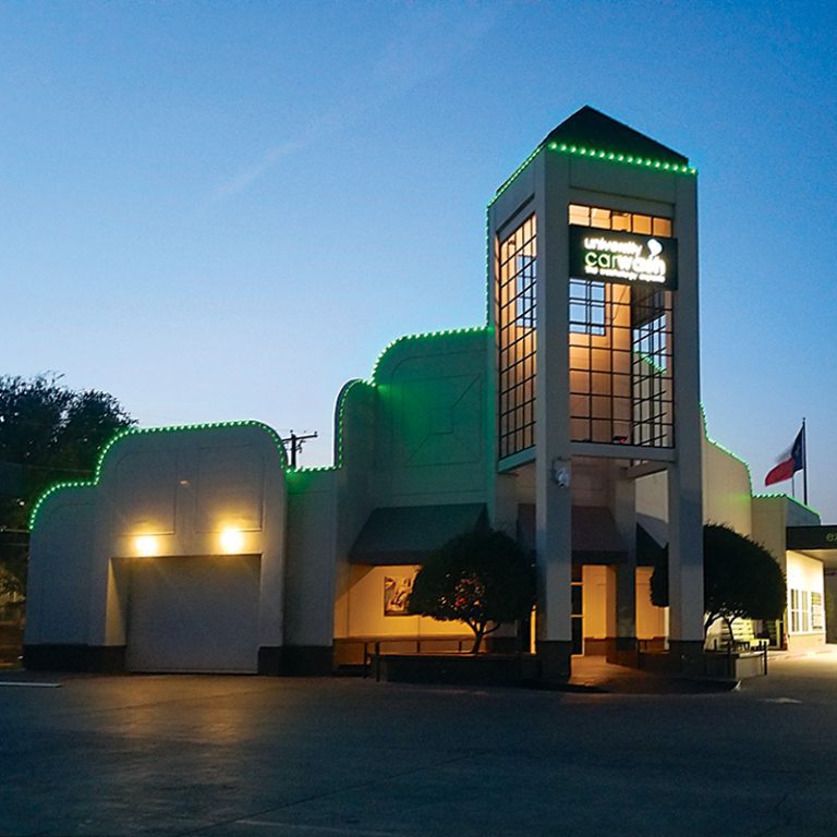 Service building with green lighting along the roofline at night.